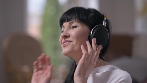 Closeup Relaxed Happy Adult Caucasian Woman Listening to Music in Headphones Enjoying Hobby Indoors