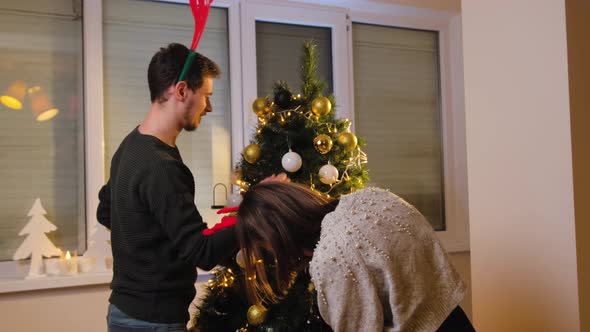 Young Couple Decorating Their Christmas Tree at Home Enjoy the Winter Holidays