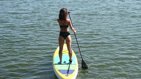 Caucasian Woman Riding a SUP Board on the Lake