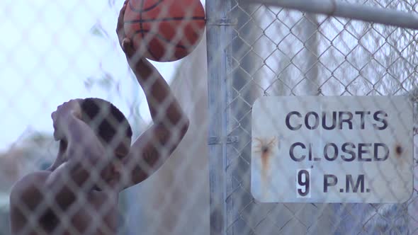 A young man playing basketball on a rainy day.