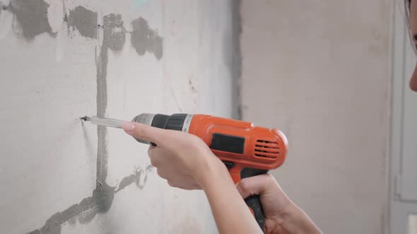 Beautiful Girl in Overalls with Electric Drill