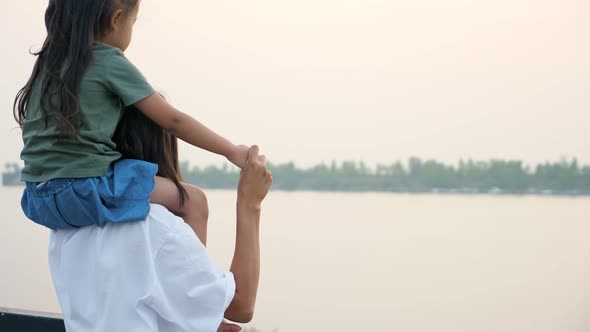 Mommy Holds Daughter on Shoulders Looking at Calm River