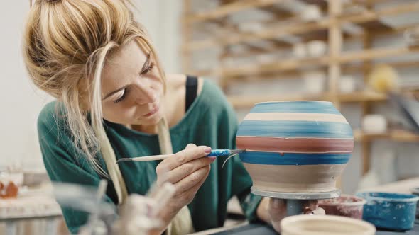 Zoom Out Shot of Pottery Artist Decorating Ceramic Pot at Pottery Workshop Slow Motion