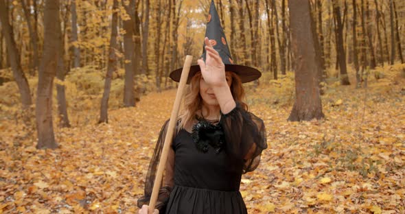 Beatiful Young Woman in Witch Costume in Autumn Park