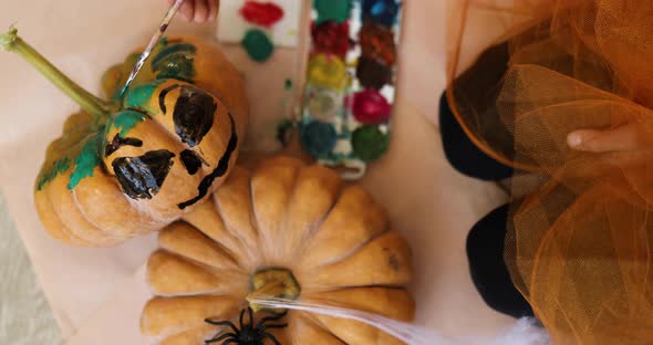 Happy child decorating a pumpkin at home with cat