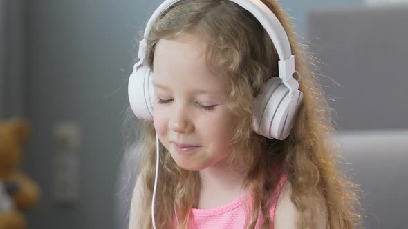 Nice Curly-Haired Girl Listening to Music in Headphones