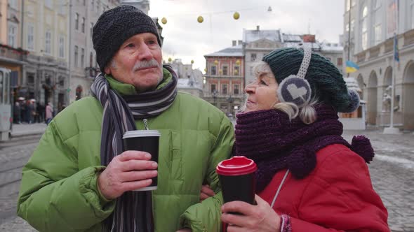 Senior Tourists Grandmother Grandfather Traveling Drinking Hot Drink Mulled Wine in City Center