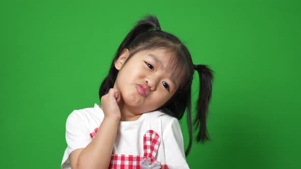 Portrait of happy and funny Asian child girl on green screen background, a child looking at camera.