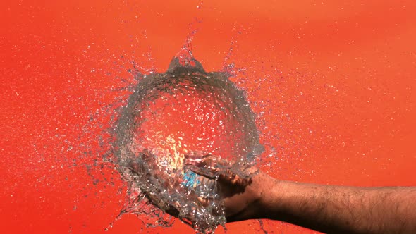 Explosion Of Blue Water Balloon In A Palm On A Terracotta Background In Slow Motion