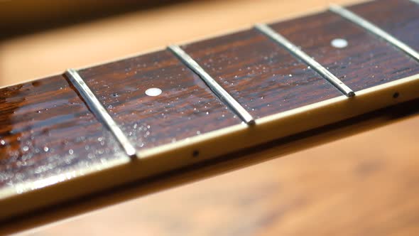 Musician cleaning and oiling an acoustic guitar neck and body.