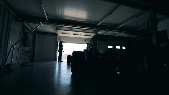 Two Men are Opening a Garage with a Racing Car in It