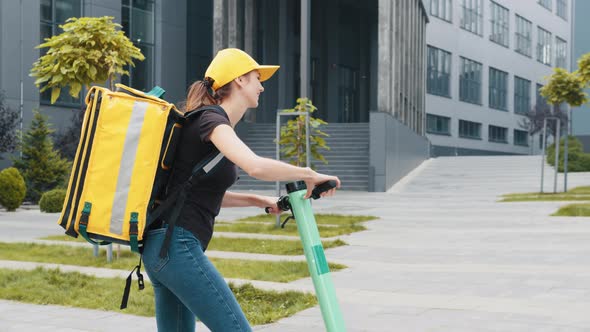 Man Courier Food Delivery with Yellow Thermal Backpack Rides the Street on an