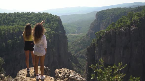 Woman Shows Green Mountains To Friend Standing on Stones