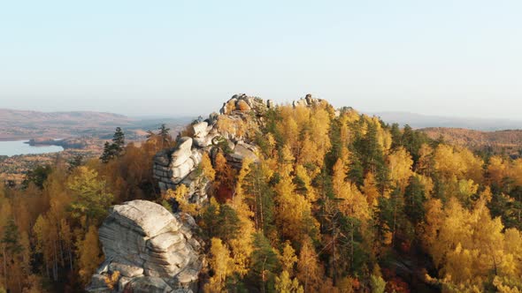 Aerial View of a Cliff Surrounded By a Colorful Autumn Forest at Sunset