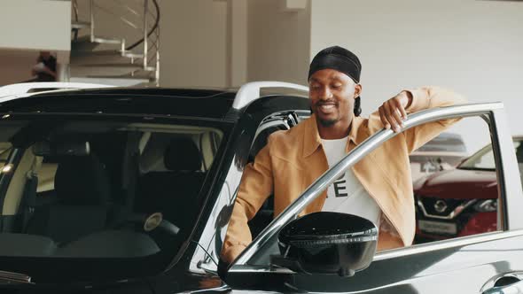 Happy African American Man Standing at Dealership Near New Luxury Car