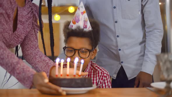 Close Up of African Mother and Father Congratulating Preteen Son Holding Birthday Cake