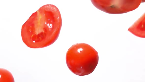 Fresh Ripe Tomato Halves are Falling Down Diagonally on the White Background
