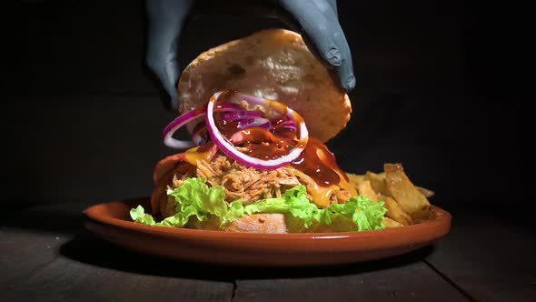 Close Up of an Unrecognizable Chef Finishing Up a Delicious Pulled Pork Burger Served with French