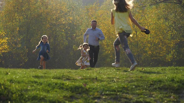 Father and daughters running in a park