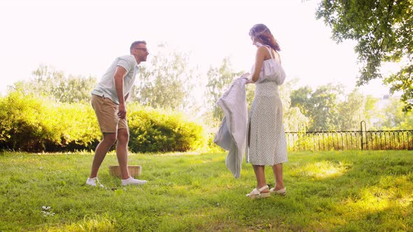 Happy Couple Laying Picnic Blanket at Summer Park