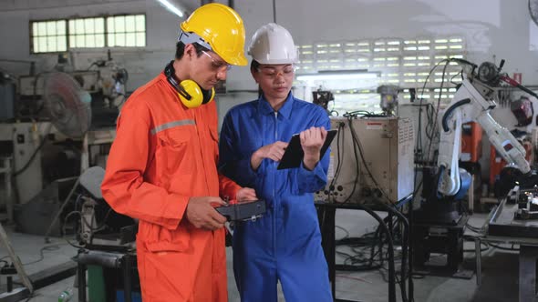 Factory workers man and woman or technician discuss about welding robot machine