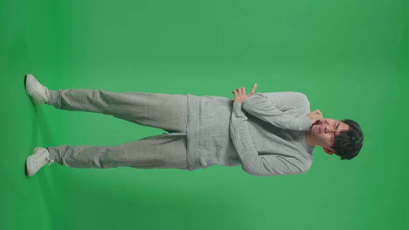 Full Body Of Asian Man Having Toothache While Standing In Front Of Green Screen Background