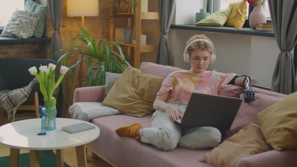 Girl with Prosthetic Arm Watching Movie on Laptop with Headphones