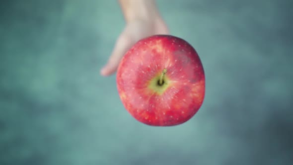 Hand Throwing Up and Catching Ripe Apple Above Table