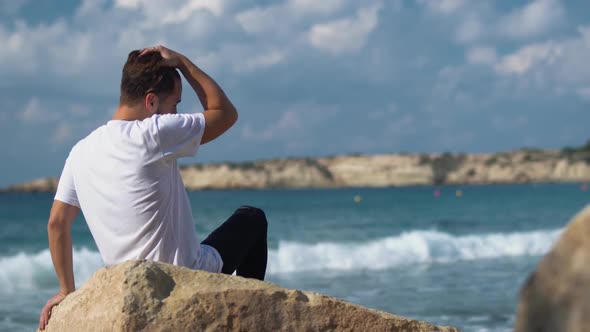 Young Handsome Man Sit on the Stone Near Amazing Sea