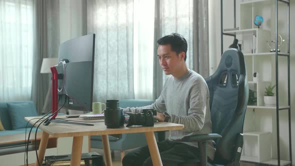 Asian Cameraman Using Desktop Computer For Working At Home