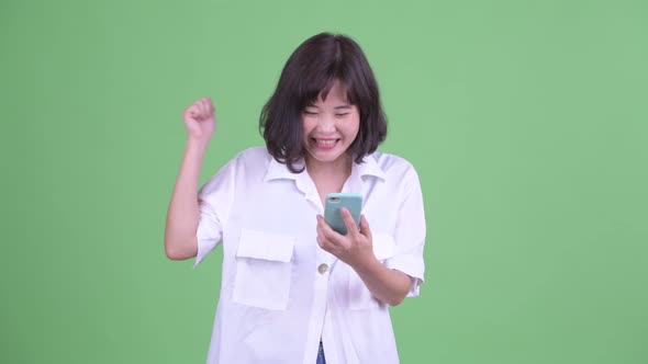 Happy Asian Businesswoman Using Phone and Getting Good News