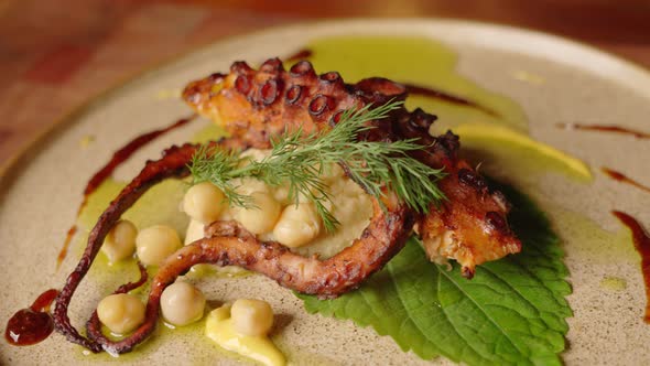 Close up slow motion shot of a complete dish of grilled octopus with chickpeas salad, beautifully ga