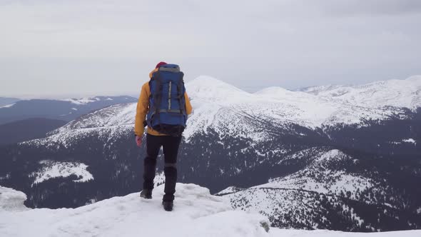 A Man with a Backpack Travels in the Mountains in Winter