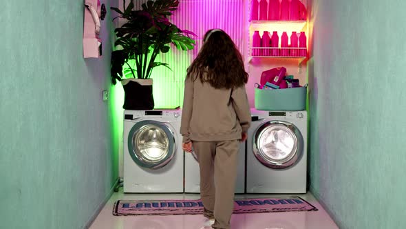 Woman with Curly Brown Hair in Beige Headphones and Beige Sports Suit Dances Against Backdrop of