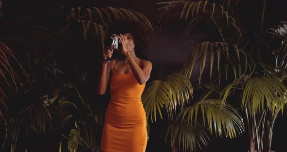 Woman With Afro Hair In Orange Dress Using Vintage 8Mm Camera