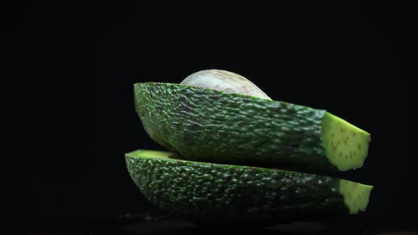 Two Halves of an Avocado Rotate in a Circle on a Black Background