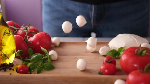 Mozzarella Cheese Small Balls Falling on Wooden Cutting Board