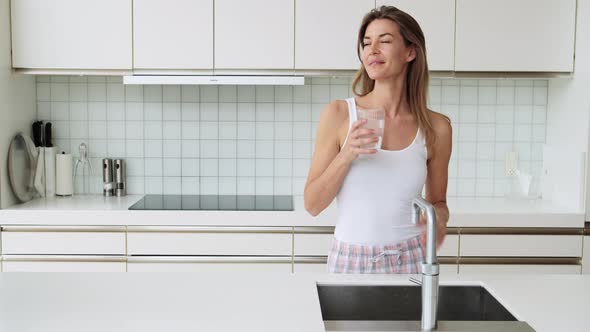 Woman in Kitchen Using Tap