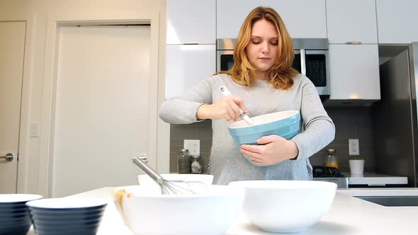 Woman mixing dough in bowl for baking