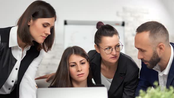 Focused Business People Discussing Analyzing Project Strategy Pointing at Screen of Laptop