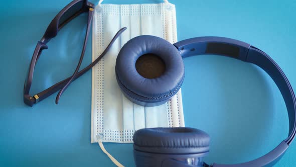 Face Mask Against Covid with Headphones and Sunglasses on Blue Background