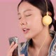 Happy pretty Asian teenager girl listening and sing a song by smartphone on pink background. - VideoHive Item for Sale