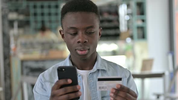 Portrait of Successful Online Payment on Phone By Young African Man