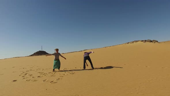 Couple dancing barefoot in desert, Egypt