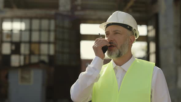 Contractor Talking By Walkie Talkie at Outdoor Building Site