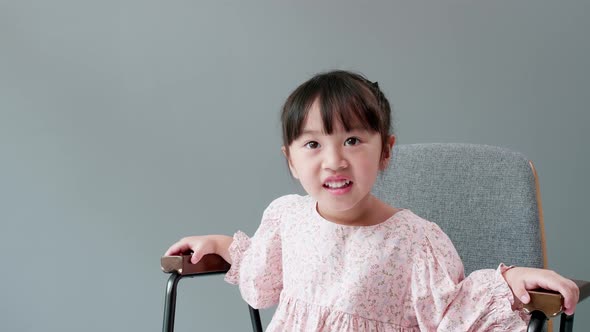 Cheerful and happy Asian children 3 Years old Sitting in a chair in front of the gray background.