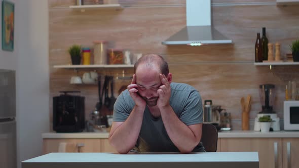 Man with Headaches Sitting in the Kitchen