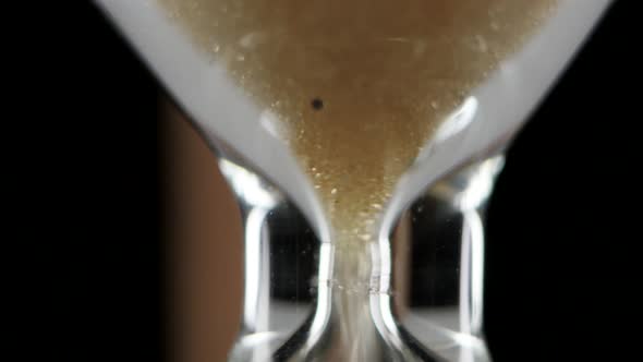 Sand Falls in Hourglass. Black. Close Up