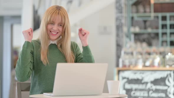 Successful Young Woman Celebrating on Laptop in Cafe