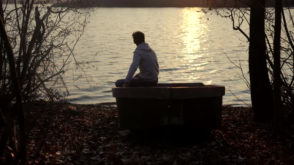 Man Sitting On Boat Near River And Enjoying The Sunset.Man Sitting Among Pond  And Looking To Sunset